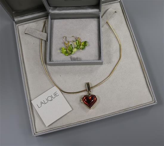 A Lalique Coeur red stone locket on chain and a pair of Lalique Papillon green crystal earrings, both boxed.